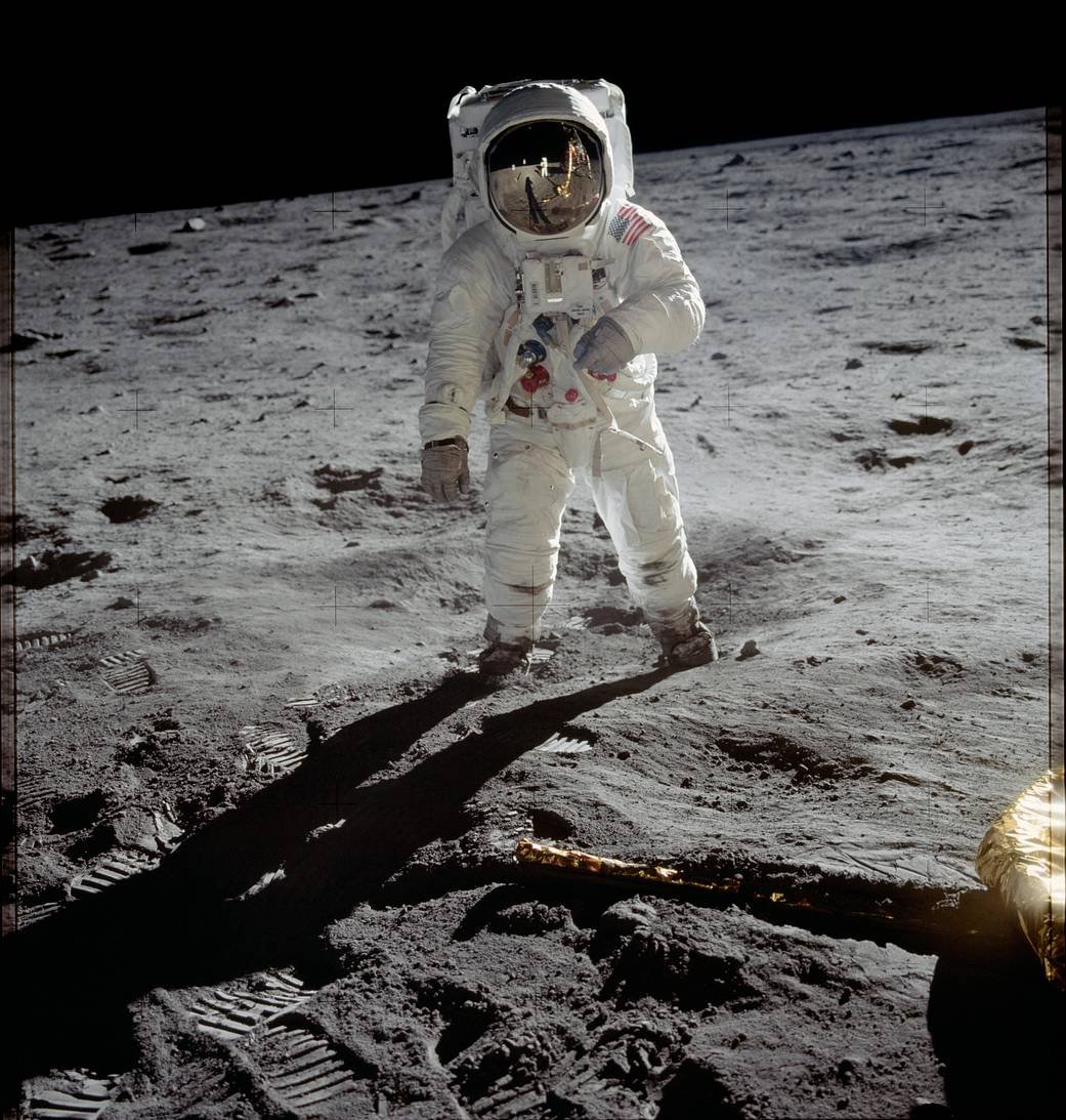 Astronaut Buzz Aldrin standing on the sunlit lunar surface beneath a completely black sky