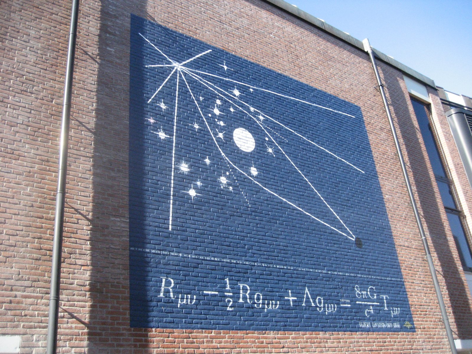 Painted wall mural of the Einstein field equation with a diagram of light bending around an eclipsed sun