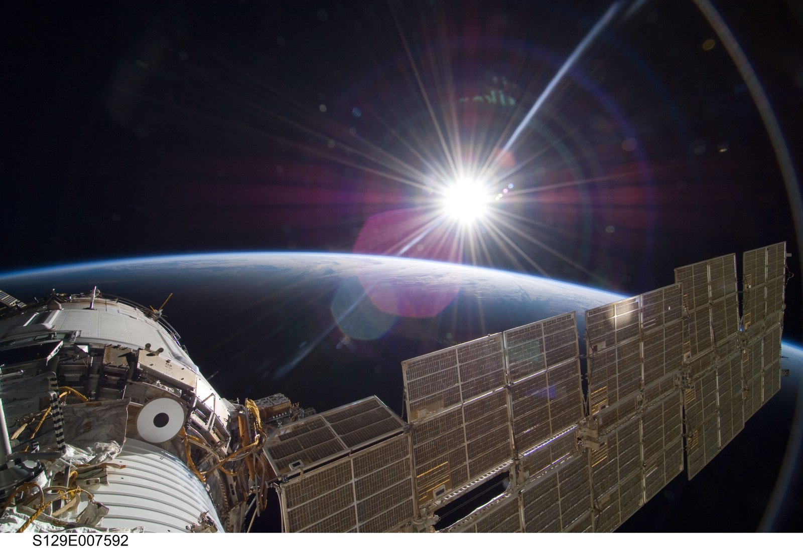 The Sun and a crescent Earth seen together from the International Space Station, showing sunlight traveling across space toward Earth