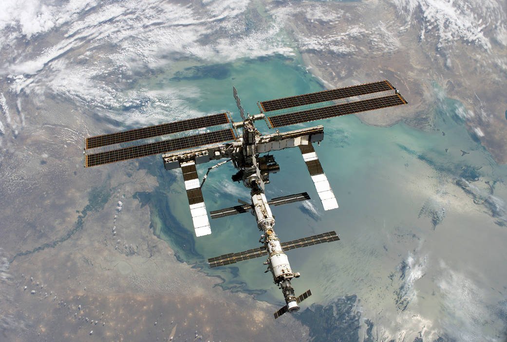 The International Space Station backdropped by Earth, an object in continuous free fall moving sideways fast enough that gravity, acting as the centripetal force, keeps it in orbit rather than falling to the surface